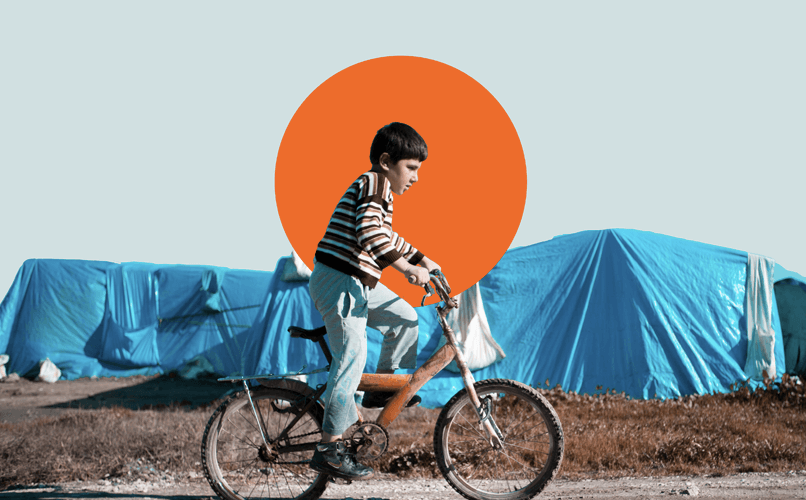 A young boy rides a bicycle in front of a row of makeshift tents covered with blue tarps. The sky is clear, and a large orange circle is superimposed in the background.