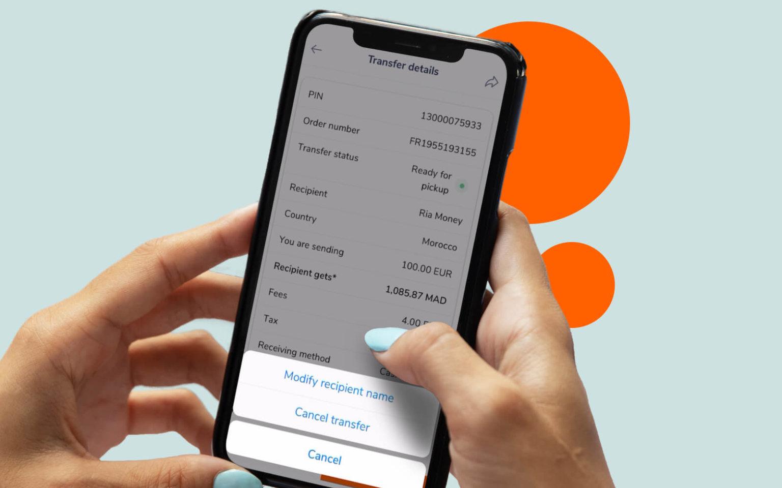 Une main tenant un smartphone affichant les détails du transfert à l'écran, notamment le code PIN, le numéro de commande et les informations sur le destinataire. Les boutons en bas indiquent « Modifier le nom du destinataire », « Annuler le transfert » et « Annuler ». L'arrière-plan comprend des cercles orange.